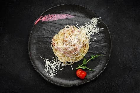 Pasta Carbonara Con Queso Y Tomates En Un Plato Negro Foto Premium