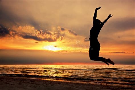 Femme Heureuse Sautant Sur La Plage Au Coucher Du Soleil Photo Stock