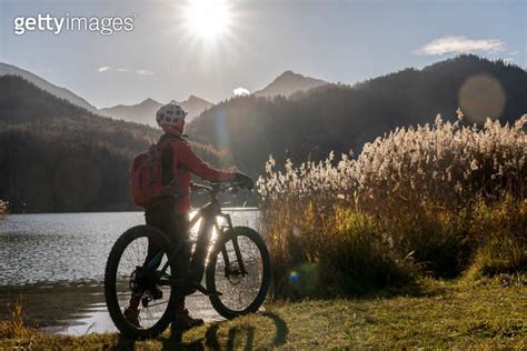 Senior Woman With Mountain Bike In Bright Backlit At Lake