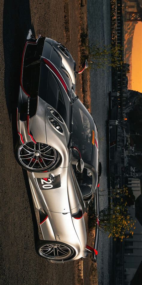 The Top View Of A Silver Sports Car Parked In Front Of A Building At Sunset