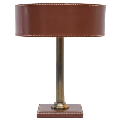 A Table Lamp With A Brown Leather Shade On The Base And A Gold Metal Base