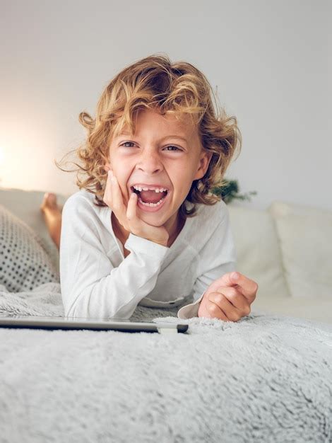 Niño preadolescente feliz acostado en el sofá y descansando con tableta