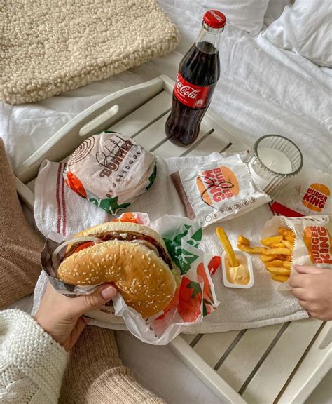 A Girl Is Holding An Impossible Whopper And You Can See Fries And Drinks In A Food Tray Behind