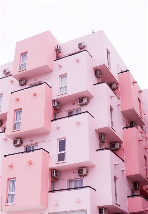 A Tall Pink Building With Balconies And Windows