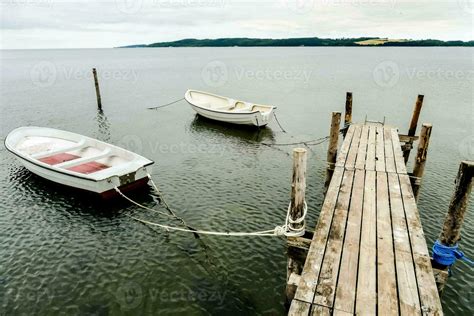 two boats tied to a dock in the water 35399576 Stock Photo at Vecteezy
