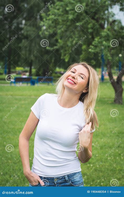 Beautiful Stylish Woman In A White Tank Top And Jeans Shorts Poses For A Photographer On The