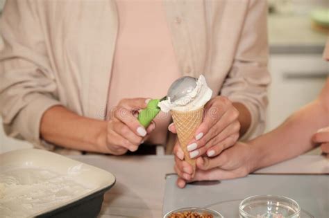 Hands Of Young Female Putting Fresh Homemade Vanilla Icecream Into