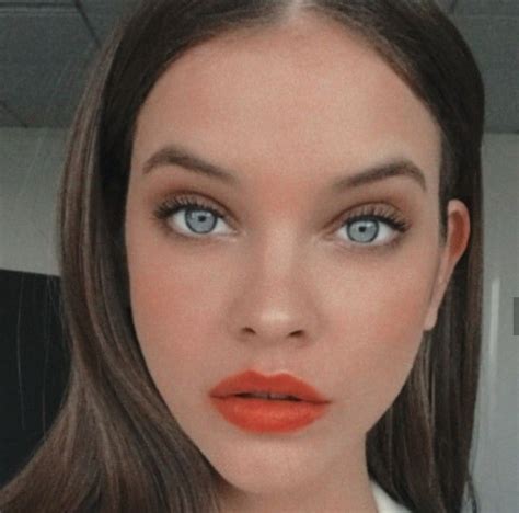 A Woman With Blue Eyes And Orange Lipstick On Her Lips Is Looking At