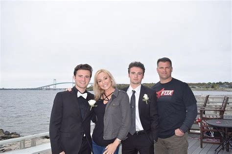 Three Men And A Woman Posing For A Picture On A Pier Near The Water