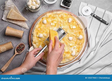 Woman Grating Cheese Onto Homemade Pizza On Table Stock Photo Image