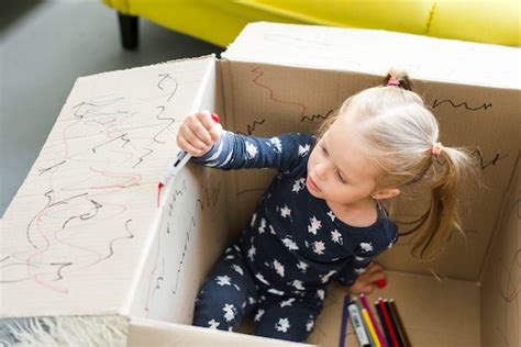 Jeune Fille Assise Dans Une Boîte En Carton Et La Décorer Avec Un