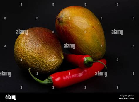 Wrinkled Mango And Smooth Mango With Red Hot Chili Pepers On Black Background Stock Photo Alamy