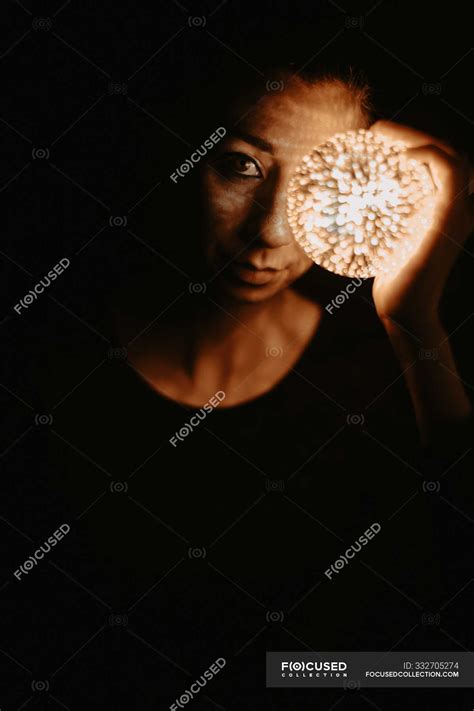 High Angle Of Naked Woman Covering Chest With Hand And Holding Luminous Ball In Dark Eccentric