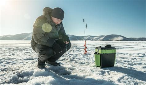 El pescador está pescando en un agujero en el hielo de un gran lago