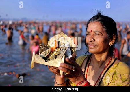 An Indian Devotee Prays To The Sun God As Others Take Holy Dips At