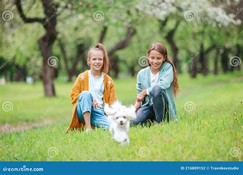 Petites Filles Souriantes Jouant Et Embrassant Chiot Dans Le Parc Photo