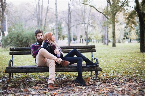 Fashionable Young Couple Sitting On A Bench In The Park By Stocksy