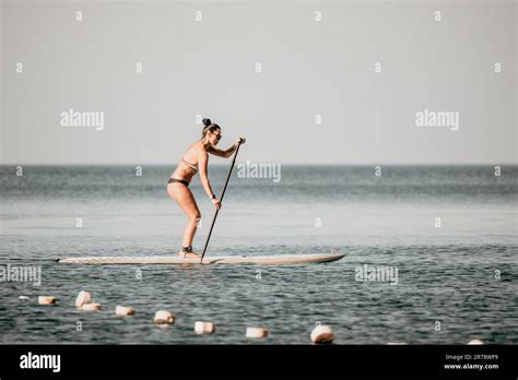 Sea woman sup Silhouette de femme bronzée d âge moyen heureuse dans un bikini arc en ciel surf