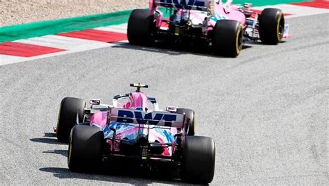 Two Racing Cars On A Race Track With One Driving Behind The Other Both