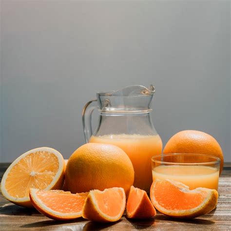 Jarra De Delicioso Jugo De Naranja Rodeado De Vasos Y Naranjas Foto