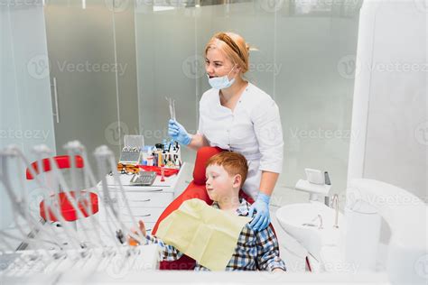 Pediatric Dentist Examining A Little Boys Teeth In The Dentists Chair At The Dental Clinic