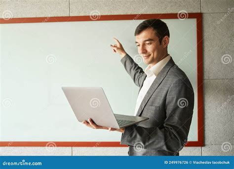 Male Teaching A Lesson Online While Pointing At Whiteboard Stock Photo