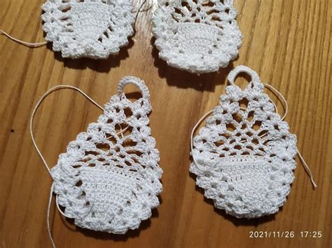 Three Crocheted White Doily Hanging On A Wooden Table With String And