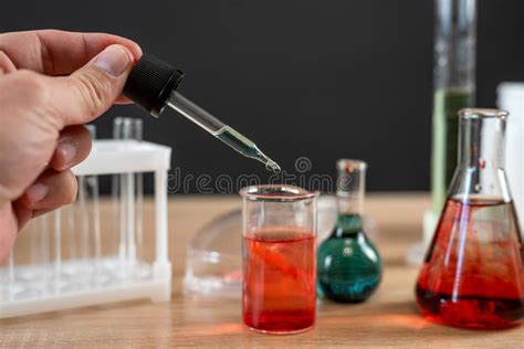 Close Up Hand With Pipette Dripping Liquid To Test Tube In Laboratory