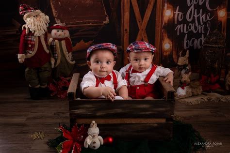 Two Babies Are Sitting In A Wooden Box With Christmas Decorations