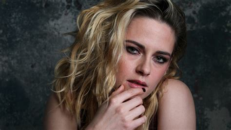 Blonde Kristen Stewart Girl Model Is Posing For A Photo Sitting In Grey Wall Background Hd Girls