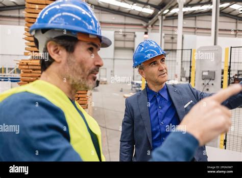 Mature Engineers Wearing Hardhat Having Discussions In Robotics Factory