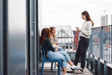 Three Female Students Chilling On The Balcony Enjoying A Study Break