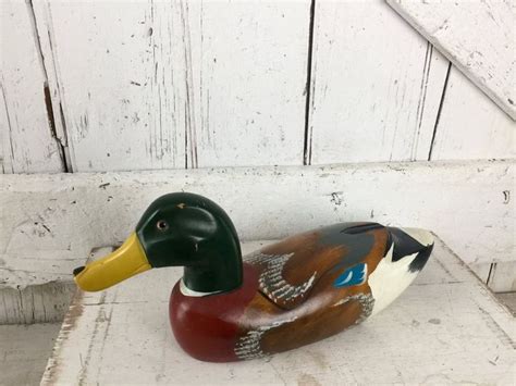 A Wooden Duck Sitting On Top Of A White Floor Next To A Wall With