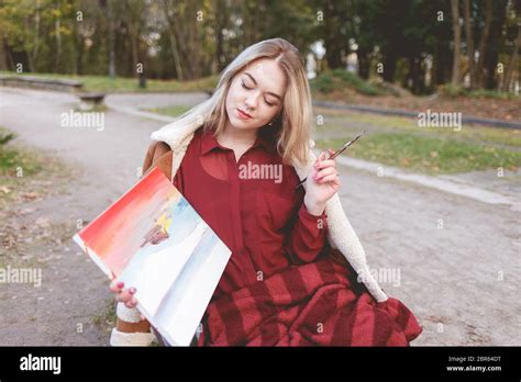 Das junge Mädchen zeichnet ein Bild auf einer Parkbank Blonde Künstlerin engagiert sich in