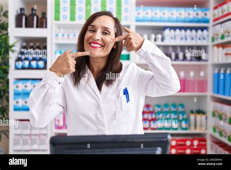 Middle Age Brunette Woman Working At Pharmacy Drugstore Smiling