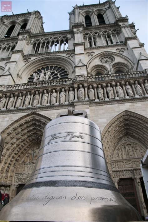 A Large Metal Bell In Front Of A Tall Building