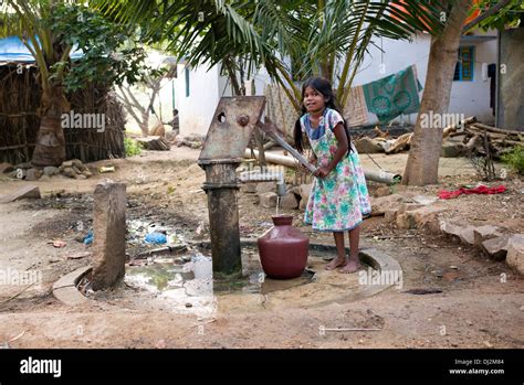 Indian Girl Filling Plastic Water Pot From A Rural Village Hand Pump