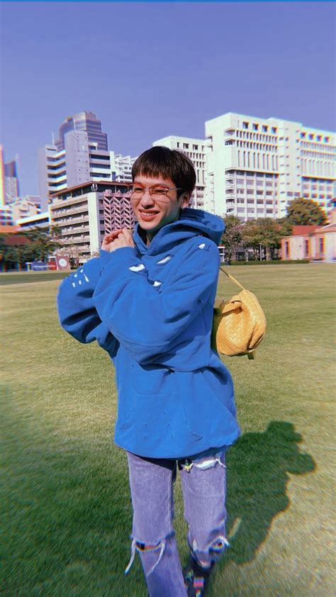 A Man Standing In The Grass With His Hand On His Ear And Wearing A Blue