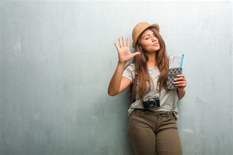 Retrato de una mujer latina joven contra una pared que muestra el número cinco Foto Premium
