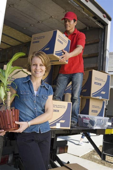 Woman With Delivery Man Unloading Moving Boxes From Truck Stock Photo