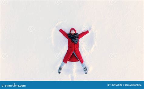 Aerial Camera Moves Out from Woman Lying in Snow and Making Snow Angel Stock Photo - Image of ...