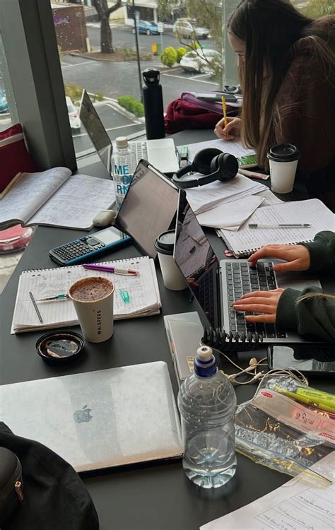 Two People Sitting At A Table With Laptops And Notebooks On Top Of Them