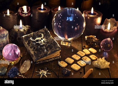 Boule de cristal, livre diabolisant et runes sur table de sorcière