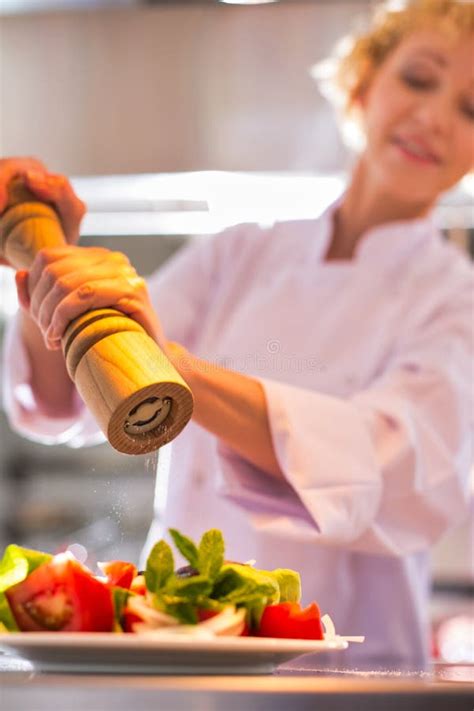 Mature Chef Using Peppermill On Salad In Plate At Restaurant Stock