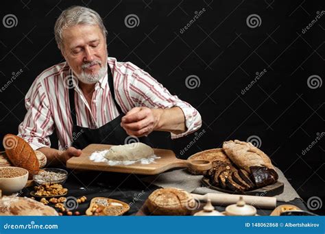 Mature Bearded Baker Man Kneading Dough For Bread On Table Stock Photo