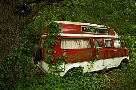 Foliage Growing On Abandoned Camper Van In Forest Stock Photo