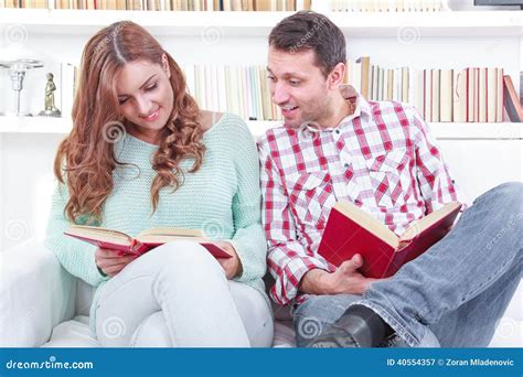 Cheerful Young Man And Woman Reading Different Books Together While