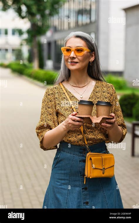 Mature Woman In Patterned Blouse And Yellow Sunglasses Standing With