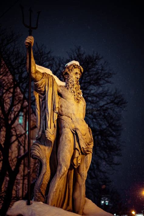Vertical Shot Of A Half Naked Male Sculpture With A Long Beard Holding A Wand During Nighttime