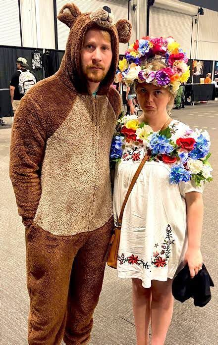 A Man And Woman Dressed In Costumes Standing Next To Each Other